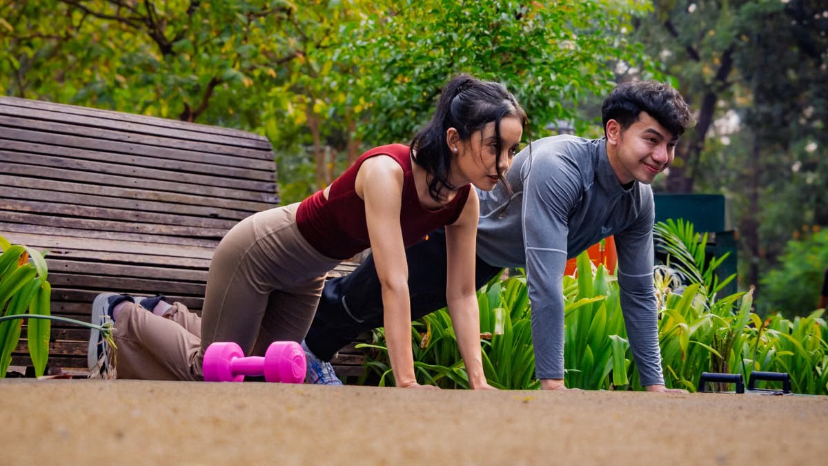 Two adults exercising in a lush Jakarta park, embracing outdoor fitness and wellness.